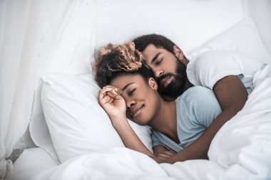 Adam yatak odasında uyuyan karısına sarılıyor.