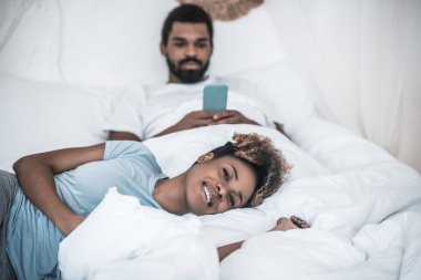 Arkasında akıllı telefonları olan neşeli yalancı kadın ve koca
