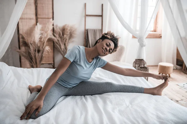 Молодая темнокожая женщина в домашней одежде на кровати — стоковое фото