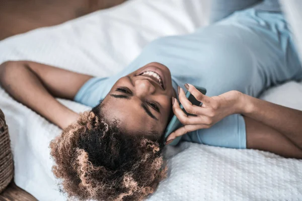 女人躺在床上用智能手机交流 — 图库照片