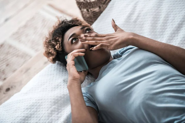 Överraskad kvinna med smartphone täcker munnen med handen — Stockfoto