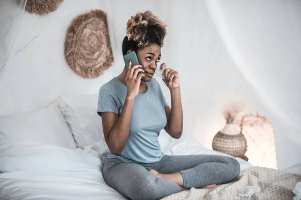Афроамериканка со смартфоном и салфеткой возле глаз — стоковое фото