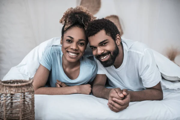 Темнокожий муж и жена лежат на кровати — стоковое фото