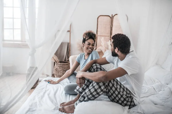 Gioioso uomo e donna dalla pelle scura seduti sul letto — Foto Stock