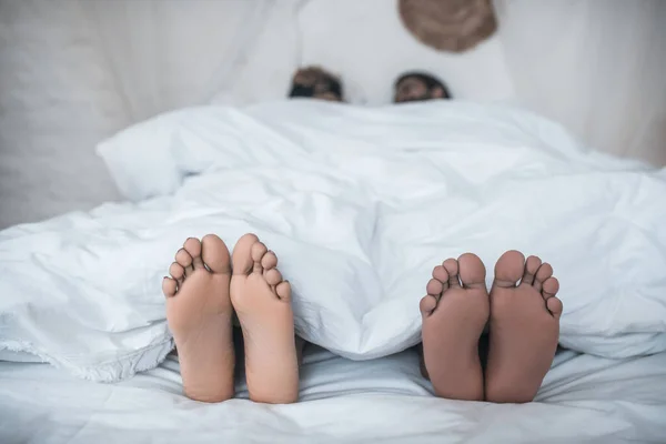 Esposo y esposa pies asomándose desde debajo de la manta — Foto de Stock