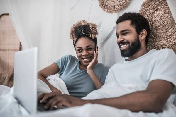 Esposo y esposa acostados en la cama mirando a la computadora portátil —  Fotos de Stock