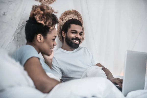 Alegre hombre y mujer mirando portátil en el dormitorio —  Fotos de Stock