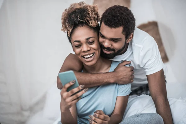 Homem abraçando mulher sentado com smartphone — Fotografia de Stock