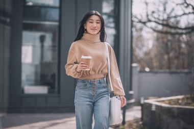 Uzun saçlı, Asyalı bir kadın sokakta yürüyor.