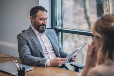 Gülümseyen önemli patron belge ve kadın asistan okuyor.