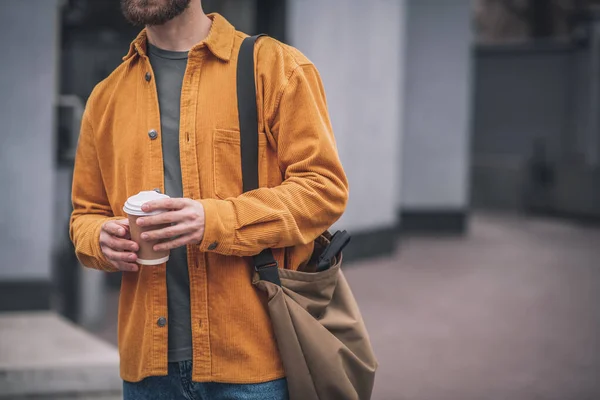 Homem de chapéu vermelho e casaco laranja com xícara de café nas mãos — Fotografia de Stock