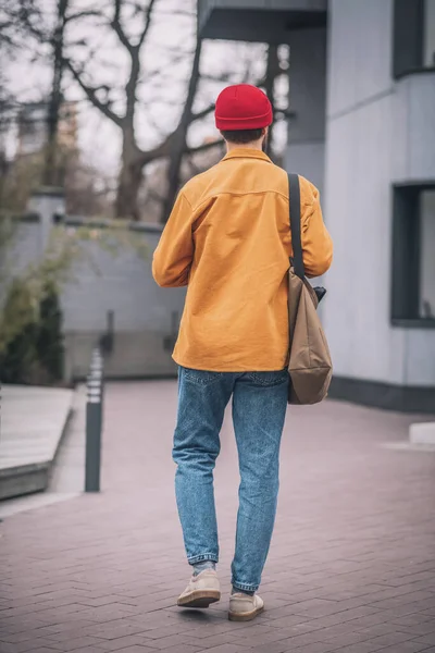 Ένας άντρας με πορτοκαλί μπουφάν που περπατάει στο δρόμο. — Φωτογραφία Αρχείου