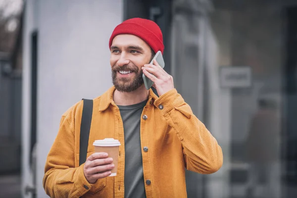 Hombre con una chaqueta naranja con un teléfono en las manos —  Fotos de Stock