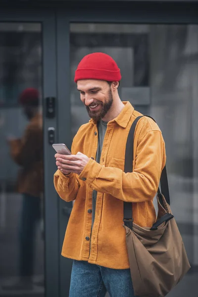 Hombre con una chaqueta naranja con un teléfono en las manos —  Fotos de Stock