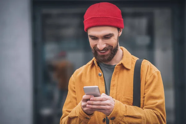 Hombre con un sombrero rojo y chaqueta naranja mirando feliz —  Fotos de Stock