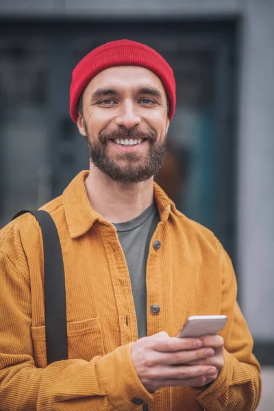 Hombre con un sombrero rojo y chaqueta naranja mirando feliz —  Fotos de Stock