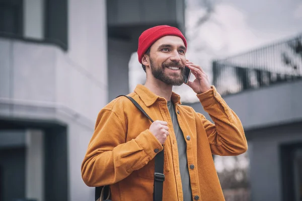 Hombre con sombrero rojo y chaqueta naranja con su smartphone en las manos —  Fotos de Stock