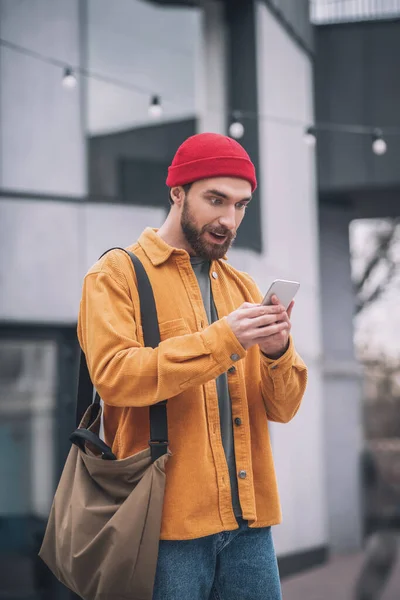 Hombre con sombrero rojo y chaqueta naranja con su smartphone en las manos —  Fotos de Stock