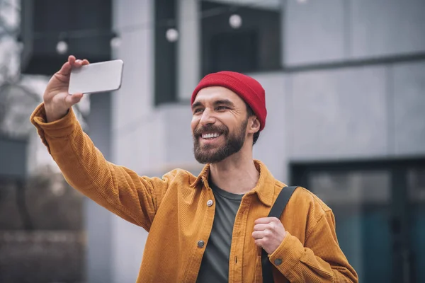 Hombre con un sombrero rojo sosteniendo su teléfono y haciendo selfie —  Fotos de Stock