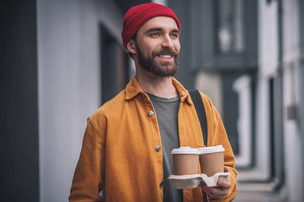 若いですbeaded男で赤い帽子を保持コーヒーカップ — ストック写真