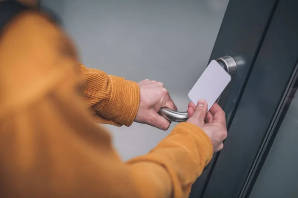 Primer plano de la mano del hombre abriendo la puerta con una tarjeta de acceso — Foto de Stock