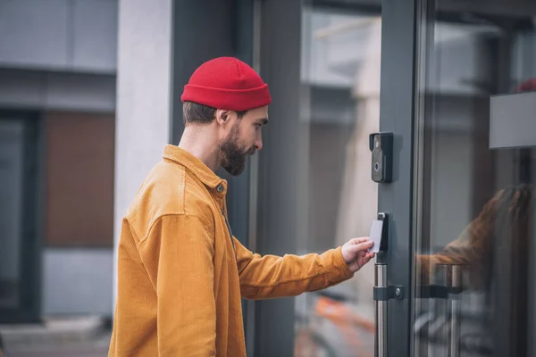 Jeune homme barbu ouvrant la porte avec une carte d'accès — Photo