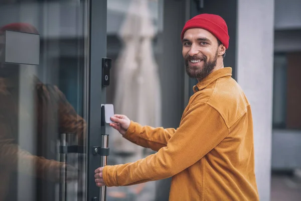 Jeune homme barbu ouvrant la porte avec une carte d'accès — Photo