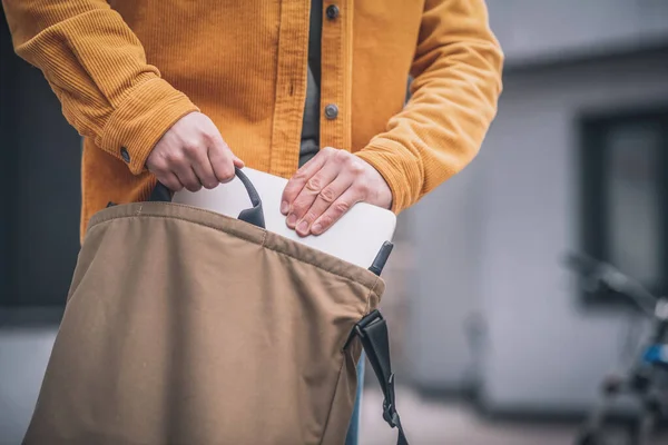 Närbild av män hand sätta laptop i en påse — Stockfoto