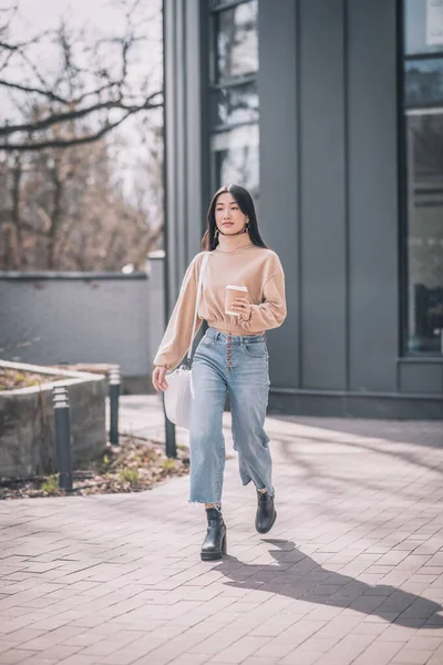 Uzun saçlı, Asyalı bir kadın sokakta yürüyor.