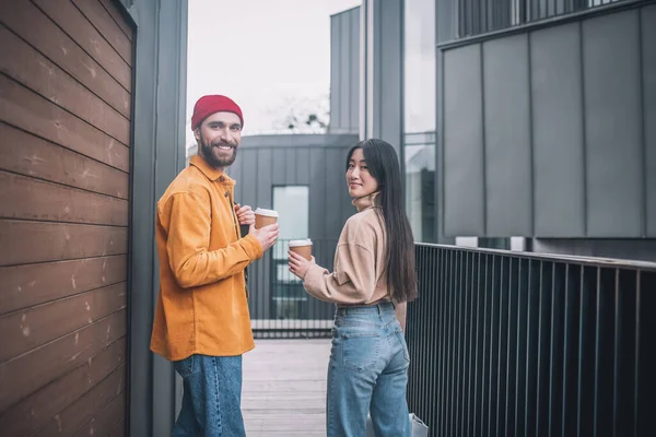 Jeune homme et femme en vêtements décontractés regardant positif tout en prenant un café à l'extérieur — Photo