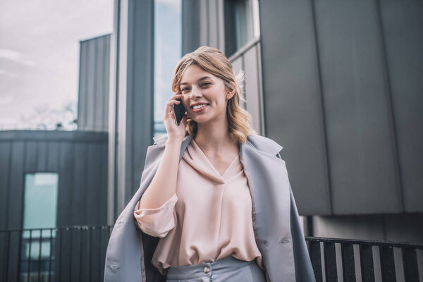 Cheerful smiling woman communicating by smartphone outdoors
