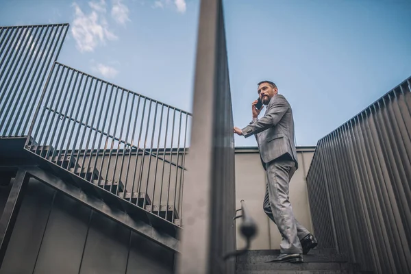 Man with smartphone climbing stairs outdoors