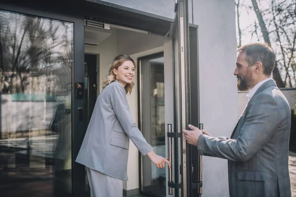 Mujer entrando a la oficina y hombre abriendo puerta — Foto de Stock