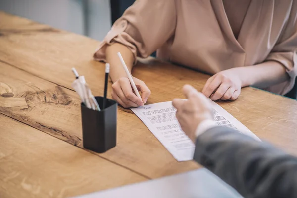 Kvinna hand underteckna dokument och man pekar — Stockfoto