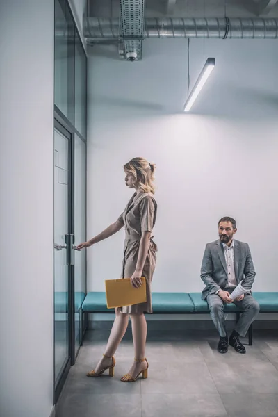 Γυναίκα εισέρχεται στο γραφείο άνθρωπος κάθεται στο διάδρομο — Φωτογραφία Αρχείου