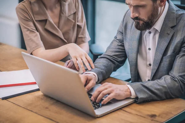 Ernsthaft fokussierter Mann arbeitet an Laptop und Frauenhand — Stockfoto