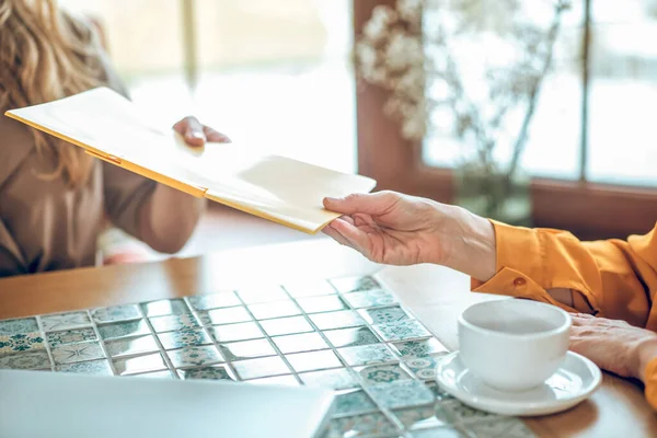 Gros plan d'une main féminine qui passe les papiers au client — Photo