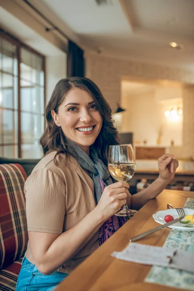 Jolie femme aux cheveux bruns assise à la table dans un restaurant et regardant rêveuse — Photo