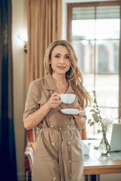 Hosszú hajú, elegáns nő teázik és elégedettnek tűnik — Stock Fotó