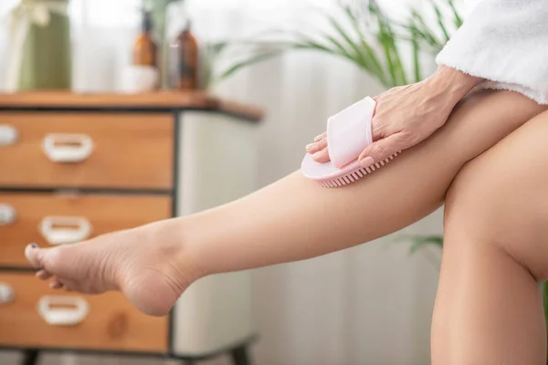 Mujer en blanco masajeando sus piernas con dispositivo de masaje —  Fotos de Stock