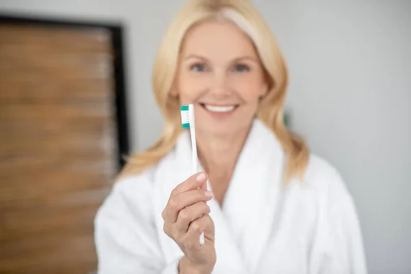 Mujer rubia sonriente cepillándose los dientes y luciendo feliz — Foto de Stock