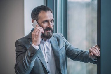 Takım elbiseli başarılı bir adam akıllı telefondan olumlu konuşuyor.