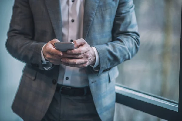 Ruce muže v šedém obleku s chytrým telefonem — Stock fotografie