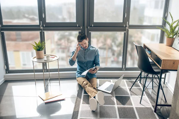 Man werkt in een kamer met grote schaduwen en kijkt betrokken — Stockfoto