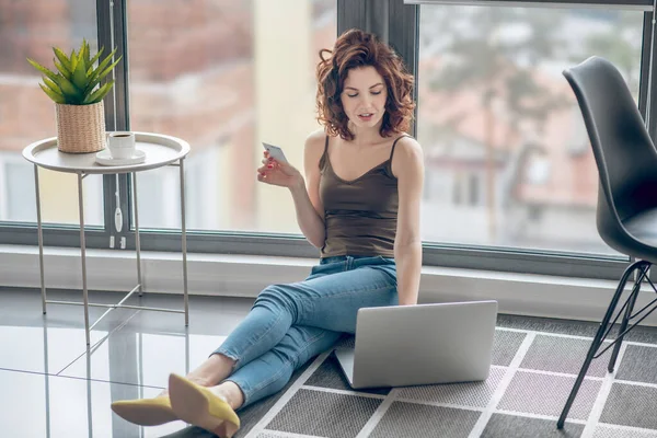 Frau arbeitet in einem Raum mit großen Fenstern und wirkt involviert — Stockfoto