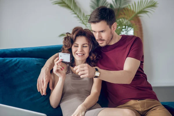 Pareja joven sentada en el sofá y eligiendo productos en línea — Foto de Stock