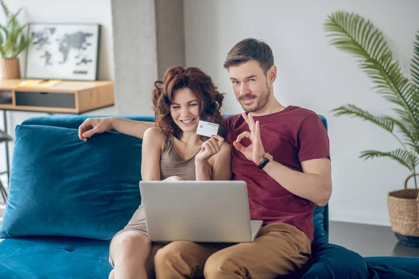 Молода пара сидить на дивані і вибирає товари онлайн — стокове фото