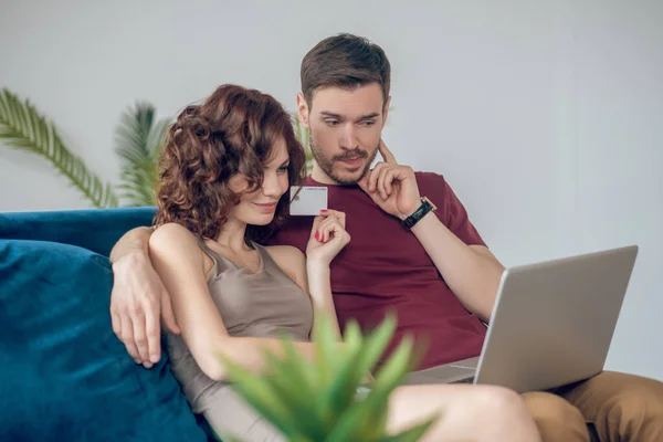 Un hombre y una mujer sentados en el sofá con un portátil — Foto de Stock