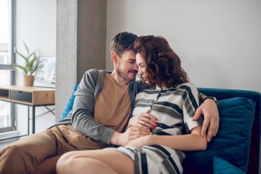 Genç çift kanepede oturuyor ve birbirlerine aşık.