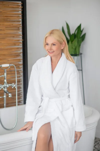 Блондинка красивая женщина в белом халате в ванной комнате — стоковое фото
